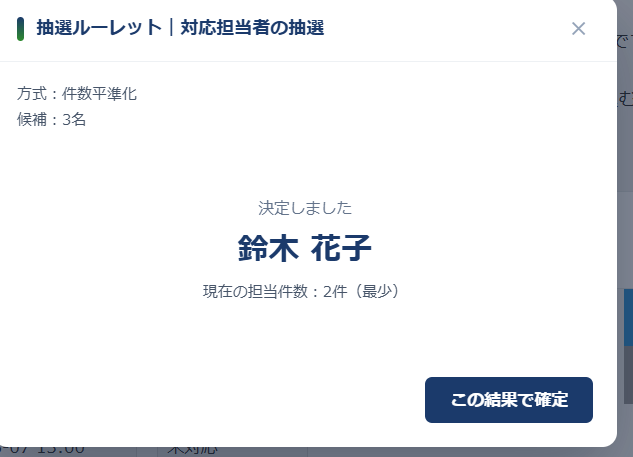 抽選ルーレットの結果画面 — 決定しましたの下に鈴木 花子と表示され、現在の担当件数は2件(最少)と添えられている